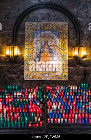 Candele votive ad un'icona dell'Abbazia di Santa Maria de Montserrat a Monistrol de Montserrat in Spagna. Foto Stock