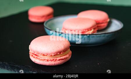 dolci concetto di pubblicità, dessert francese - macaroon rosa su sfondo nero, primo piano Foto Stock