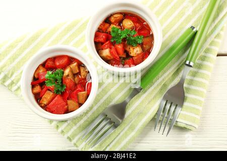 Gustosa ratatouille vegetariana a base di melanzane, squash, pomodori in ciotole su sfondo di tavolo in legno Foto Stock