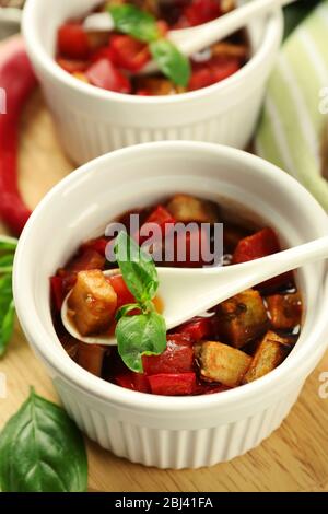 Gustosa ratatouille vegetariana a base di melanzane, squash, pomodori in ciotole su sfondo di tavolo in legno Foto Stock