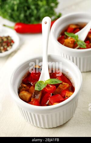 Gustosa ratatouille vegetariana a base di melanzane, squash, pomodori in ciotole su sfondo di tavolo in legno Foto Stock