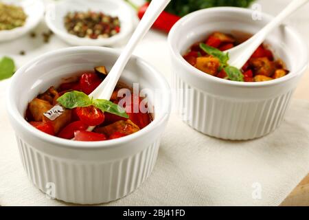 Gustosa ratatouille vegetariana a base di melanzane, squash, pomodori in ciotole su sfondo di tavolo in legno Foto Stock