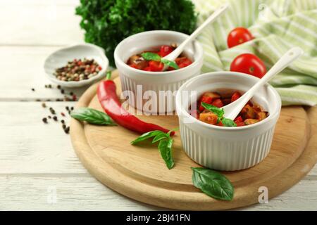 Gustosa ratatouille vegetariana a base di melanzane, squash, pomodori in ciotole su sfondo di tavolo in legno Foto Stock