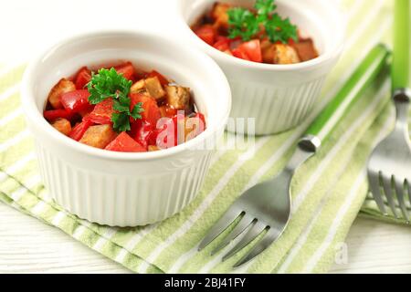 Gustosa ratatouille vegetariana a base di melanzane, squash, pomodori in ciotole su sfondo di tavolo in legno Foto Stock