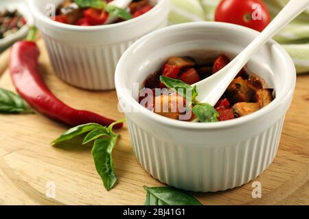 Gustosa ratatouille vegetariana a base di melanzane, squash, pomodori in ciotole su sfondo di tavolo in legno Foto Stock