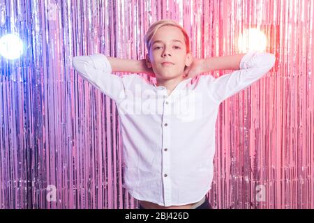 Età scomoda e concetto adolescente - Ritratto di ragazzo teen ad una festa. Sfondo lucido. Foto Stock