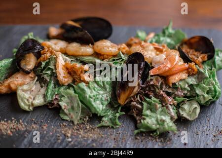 Insalata di pesce. Insalata calda con foglie, gamberi, cozze e sause. Foto Stock