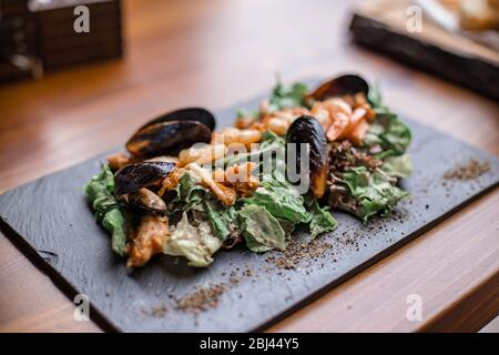 Insalata di pesce. Insalata calda con foglie, gamberi, cozze e sause. Foto Stock