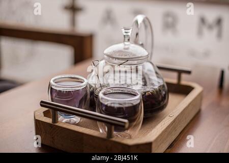 Il tè alle erbe floreale viola viene versato dal produttore nella tazza. Foto Stock