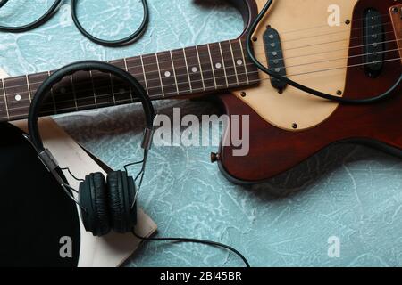 Chitarra elettrica e cuffie con accessori musicali su sfondo grigio Foto Stock