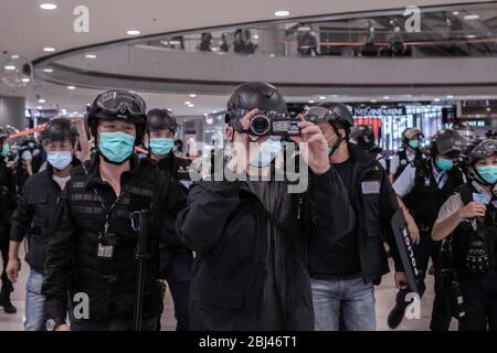 Hong Kong, Cina. 28 Aprile 2020. Un agente di polizia filma il pubblico durante l'azione contro i manifestanti al centro commerciale IFC di Hong Kong. La polizia di martedì sera ha rotto un tentativo di protesta al centro commerciale di lusso IFC a Central. Gli ufficiali hanno cordonato una parte dell'atrio e sono stati emessi diversi biglietti a pena fissa per le persone che hanno violato le regole di distanza sociale. Le regole vietano le riunioni pubbliche di più di quattro persone a causa della pandemia di Covid-19. Credit: SOPA Images Limited/Alamy Live News Foto Stock