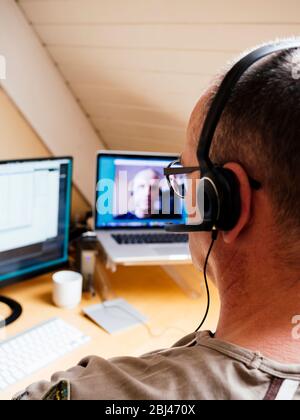 Uomo in ufficio a casa che ha una videochiamata con un collega. Foto Stock