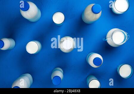 Collezione di bottiglie e bicchieri con latte su sfondo blu, vista dall'alto Foto Stock