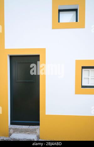 Colori tipici di Evora - casa scatola geometrica bianca e gialla con porta anteriore verde scuro in strada a Evora, Portogallo Foto Stock
