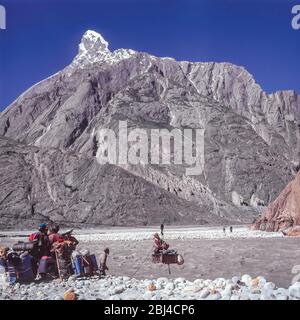 Pakistan, zone settentrionali delle montagne di Karakoram. Un gruppo europeo di trekking condivide il compito comune di caricare la scatola Jola per aiutare l'attraversamento del fiume Braldu alla testa della gola di Braldu. La Jola è stata sostituita da un ponte di sospensione che rende l'operazione più facile e sicura Foto Stock