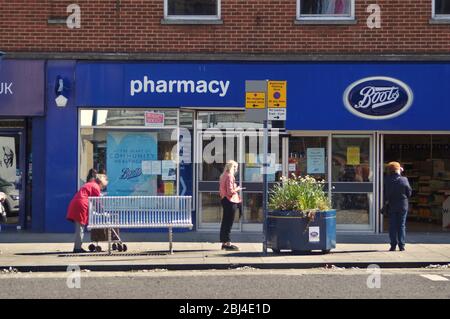 Distanziamento sociale delle persone durante la pandemia di COVID mentre fanno la coda fuori dalla farmacia Boots a BOSTON Lincolnshire, Foto Stock