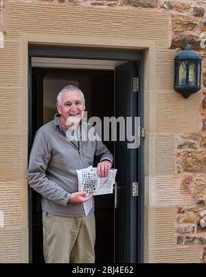 Camptoun, East Lothian, Scozia, Regno Unito. 28 Apr 2020. Una comunità in blocco: I residenti in una piccola comunità rurale mostrano come è la vita in blocco per loro. Nella foto: Mike, in pensione e 67 anni, è un appassionato solutore di crossword, ed è entrato in centinaia di concorsi di crossword Foto Stock