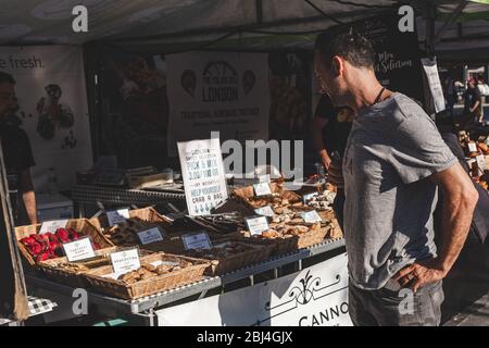 London/UK-26/07/18: L'uomo sceglie dolci in una stalla al mercato alimentare reale di Kings Cross. Dove conveniente, una fermata negozi del t. Attentamente selezionato Foto Stock