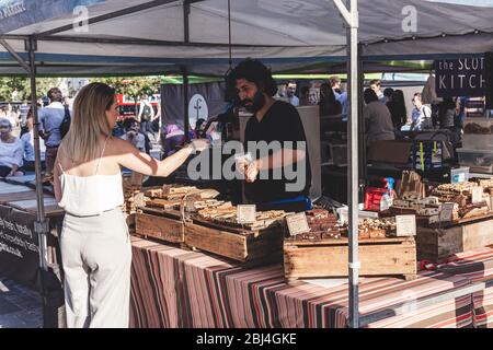 Londra/UK-26/07/18: Donna che acquista dolci nella stalla 'Outsider Tart' al mercato alimentare reale di Kings Cross, dove si trovano negozi convenienti e unici Foto Stock