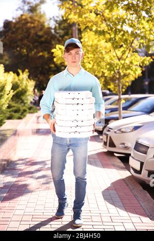 Consegna pizza ragazzo che tiene scatole con pizza, all'aperto Foto Stock