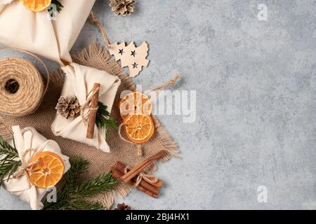 Zero spreco di natale concetto. Confezionato in tessuti naturali regali e decorazioni di materiali naturali su un tavolo grigio, vista dall'alto, spazio copia. Foto Stock