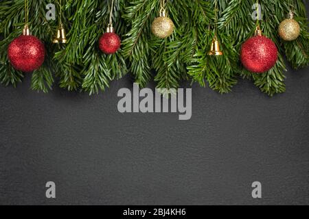 Rami di albero di Natale con decorazioni rosse su sfondo nero. Modello per biglietto di auguri o disegno. Banner orizzontale con spazio di copia. Foto Stock