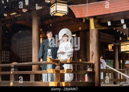 Sposa e sposo scattando foto di matrimonio al Santuario Meiji di Tokyo, Giappone. Saranno poi condotti da sacerdoti e fanciulle alla cerimonia vera e propria Foto Stock