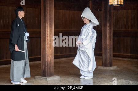 Sposa e sposo scattando foto di matrimonio al Santuario Meiji di Tokyo, Giappone. Saranno poi condotti da sacerdoti e fanciulle alla cerimonia vera e propria Foto Stock