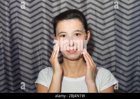 Ragazza in una maschera facciale cosmetica. Fa trattamenti di bellezza fatti in casa. Foto ravvicinata Foto Stock