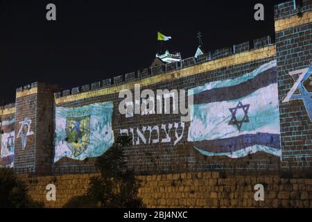 Gerusalemme, Israele. 28 Aprile 2020. La bandiera israeliana e l'emblema di Gerusalemme sono proiettati sulle mura della Città Vecchia di Gerusalemme, mentre Israele celebra 72 anni di indipendenza tra la pandemia del coronavirus COVID-19. Il blocco del giorno dell'indipendenza ha effetto come gli israeliani legati alle case. Foto Stock