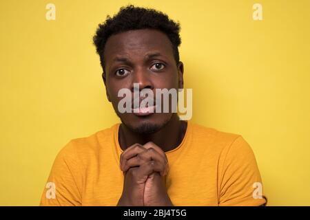 Giovane afroamericano che prega sperando per il migliore chiedere per perdono Foto Stock