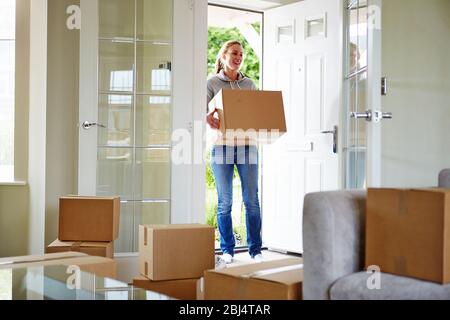 Giovane donna si spostano in un nuovo appartamento tenendo le scatole di cartone con oggetti personali Foto Stock