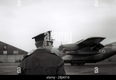 Una guardia di sicurezza e un grande aereo guidato da un propellore in uno spettacolo aereo in Lancashire, Inghilterra, Regno Unito, all'inizio degli anni '70. Foto Stock