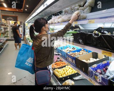 Gold Coast, Australia - 29 aprile 2020: Asian femminile indossa maschera medica protettiva nel negozio di alimentari asiatico in mezzo a paure di coronavirus, sicurezza supermercato, Foto Stock