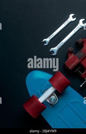 Attrezzi di riparazione e skateboard blu con ruote rosse su sfondo grigio, vista dall'alto Foto Stock