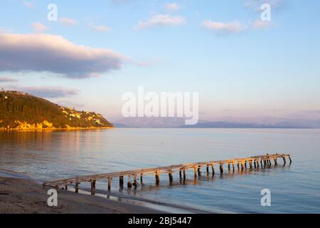 Molo in legno sulla spiaggia di Dassia all'alba, Corfù, Grecia Foto Stock