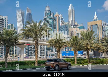 Lussureggianti strade fiancheggiate da palme di fronte al Dubai Marina. Foto Stock