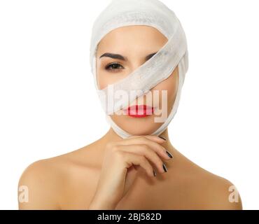 Giovane donna giocosa con bendaggio garza sulla testa e sul petto, su sfondo nero Foto Stock