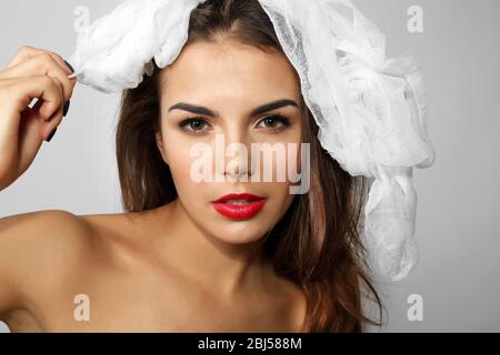 Giovane bella donna con garza sulla testa, su sfondo grigio Foto Stock