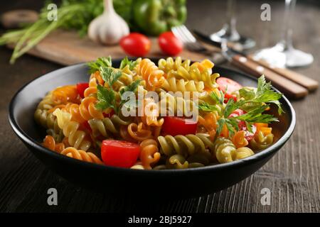 Delizioso piatto di maccheroni in ciotola nera su tavolo di legno servito Foto Stock