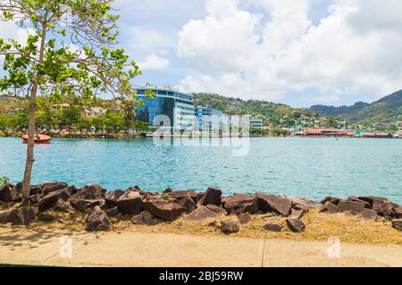 Castries, Santa Lucia - Aprile 15 2020: L'acqua del porto Castries tra rocce sul lato vicino e colline e edifici sullo sfondo Foto Stock