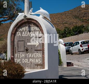 Akrotiri, Grecia - Luglio 19 2019: Un cartello che indica la Taverna dei Delfini sulla strada della Spiaggia Rossa Foto Stock