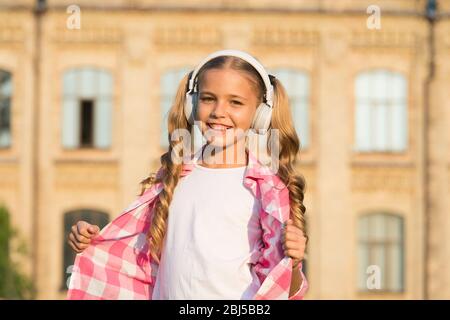 ragazza felice scuola indossare auricolari. bambina stile casual all'aperto. vacanza primaverile appena iniziato. la sua playlist estiva preferita. bambino ascoltare musica. sorridente bambino ascoltare audio libro. Foto Stock