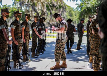 U.S. Marine Corps SSgt Maxime Faulkner, un istruttore di perforazione con il secondo Battaglione di addestramento del reclutamento, ispeziona un reclutamento mentre indossa una maschera facciale per prevenire la diffusione di COVID-19, coronavirus Aprile, 27, 2020 a Marine Corps Recruit Depot Parris Island, South Carolina. Foto Stock