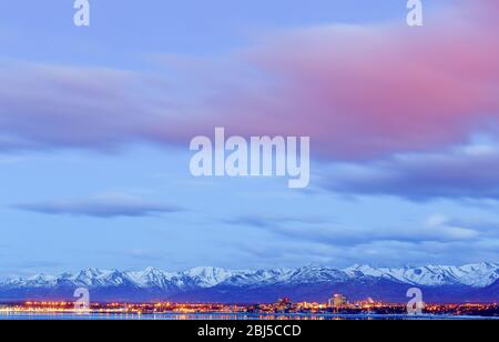 Anchorage Alaska skyline con Chugach montagne sullo sfondo al tramonto visto attraverso Cook Inlet dal parco terremoto in inverno. Foto Stock