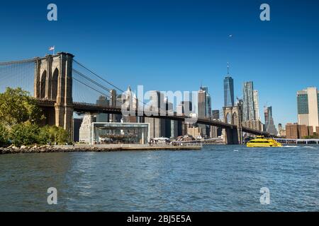 Passeggiata sul lungomare del fiume Est sotto il ponte di Brooklyn, vista dall'area DUMBO a New York USA Foto Stock