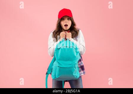 Non è così. Trasporto di oggetti in zaino. Scopri come montare correttamente lo zaino. Zaino per bambini alla moda ragazza. Utile accessorio di moda. Scolaretta rossa cappuccio capelli lunghi con zaino scuola. Foto Stock