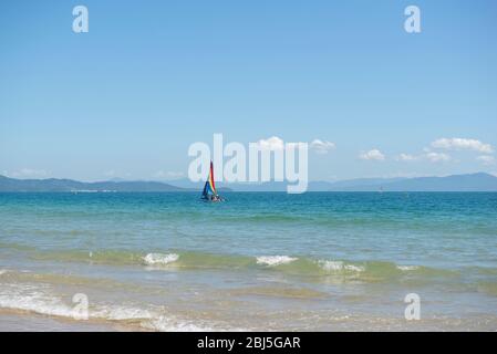 Piccola barca a vela colorata in catamarano nel mare blu. Barca a vela catamarano con vela colorate sul mare. Yachting. Brasile, acque turchesi di Atla Foto Stock