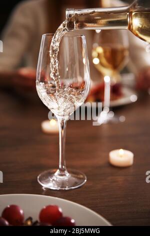 Versare il vino bianco dalla bottiglia nel vitigno Foto Stock