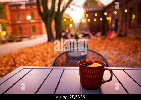 Lodz, Polonia: Una tazza di bevanda calda al tavolo nella districa storica di Ksiezy Mlyn durante la serata d'autunno Foto Stock